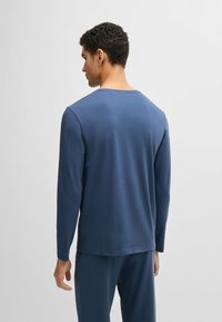 Långärmad t-shirt med rund halsringning i mörkblått, tillverkad av mjukt material. Har en slät yta med rak passform och minimalistisk design.