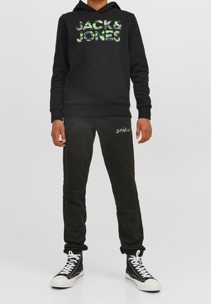 Sweat à capuche noir avec logo imprimé camouflage, pantalon de survêtement noir avec petit logo, et baskets montantes noires à semelles blanches. Coupe décontractée et confortable.