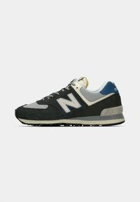 Fekete és szürke sneaker, velúr és hálós anyagokból készült. Kék akcentussal, jellegzetes 'N' logóval és mintázott gumi talppal rendelkezik.