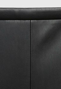 Rivestimento in pelle nera con una texture liscia e sottili motivi a grana, diviso da una cucitura verticale per dare struttura.