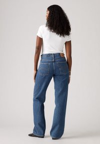 Hoge taille blauwe denim jeans met een rechte pijp en zichtbare achterzakken. Bevat een leren merklabel op de tailleband en een onafgewerkte zoom.