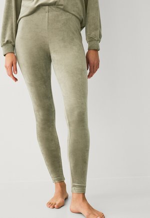 Olivgrüne, weiche, samtige Leggings mit passgenauer Form und elastischem Bund, kombiniert mit einem lockeren Langarmoberteil.