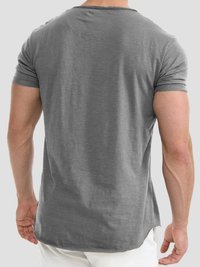 Grijze t-shirt met korte mouwen, een losse pasvorm, ronde halslijn en een ongelijkmatige zoom. Gemaakt van zachte stof met een lichte glans en zichtbare stikseldetails.
