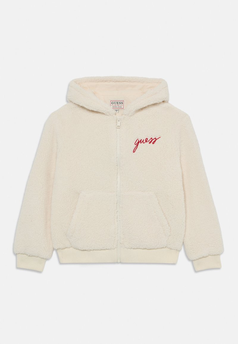 Sweatshirt com fecho éclair em creme, apresentando uma textura suave, dois bolsos frontais e bordado em vermelho de "guess" no lado esquerdo do peito.