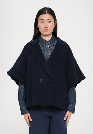 Navy wool blend double-breasted jacket with wide sleeves, large collar, and two front pockets, layered over a blue patterned shirt.