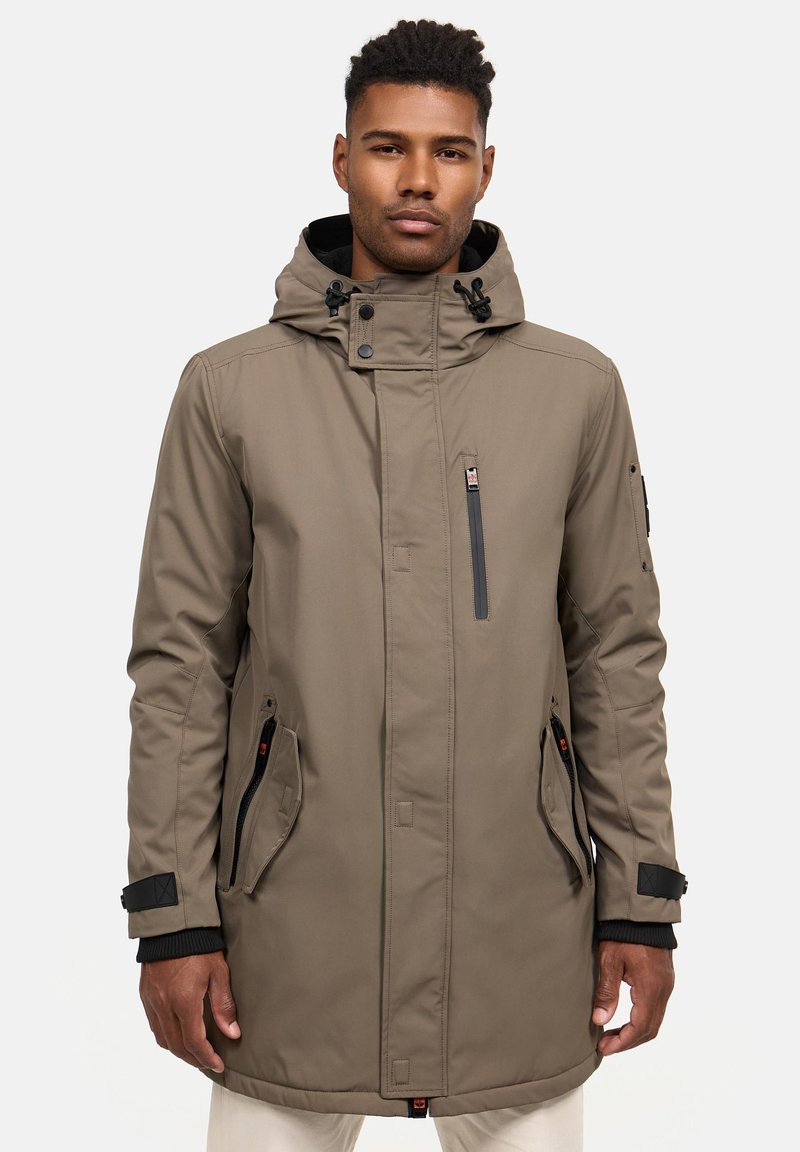 Khaki parka ar rāvējslēdzēju un pogu aizdari, regulējamu kapuci, sānu kabatām un plaukstas siksnām. Gluda, ūdensizturīga auduma.