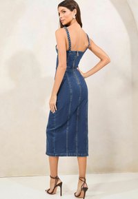 Denim midi obleka z pletenimi ramnimi trakovi, prilegajočim topom, vidnimi šivi in zadrgo na hrbtu; temno modra barva in gladka tekstura.