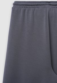 Graue Sporthosen mit einem elastischen Bund, glatter Textur und tailliertem Bein. Der Stoff hat ein weiches, leichtes Aussehen.