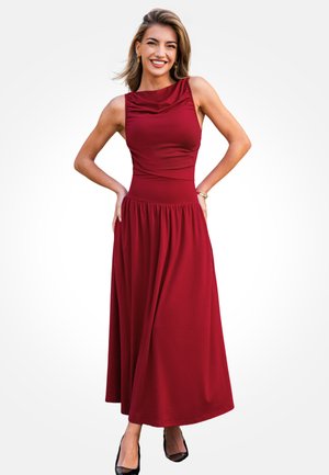 Bordeauxrode, mouwloze maxi-jurk met een geplooide, ronde halslijn, een aansluitend lijfje en een uitlopende rok tot aan de enkels. Gecombineerd met zwarte hakken.
