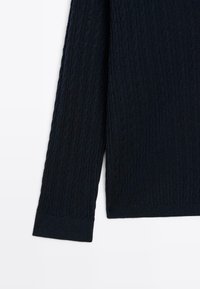 Maglione lavorato a maglia a trecce colore navy con maniche lunghe e polsini a costine. La texture è morbida e presenta un motivo in rilievo intrecciato.