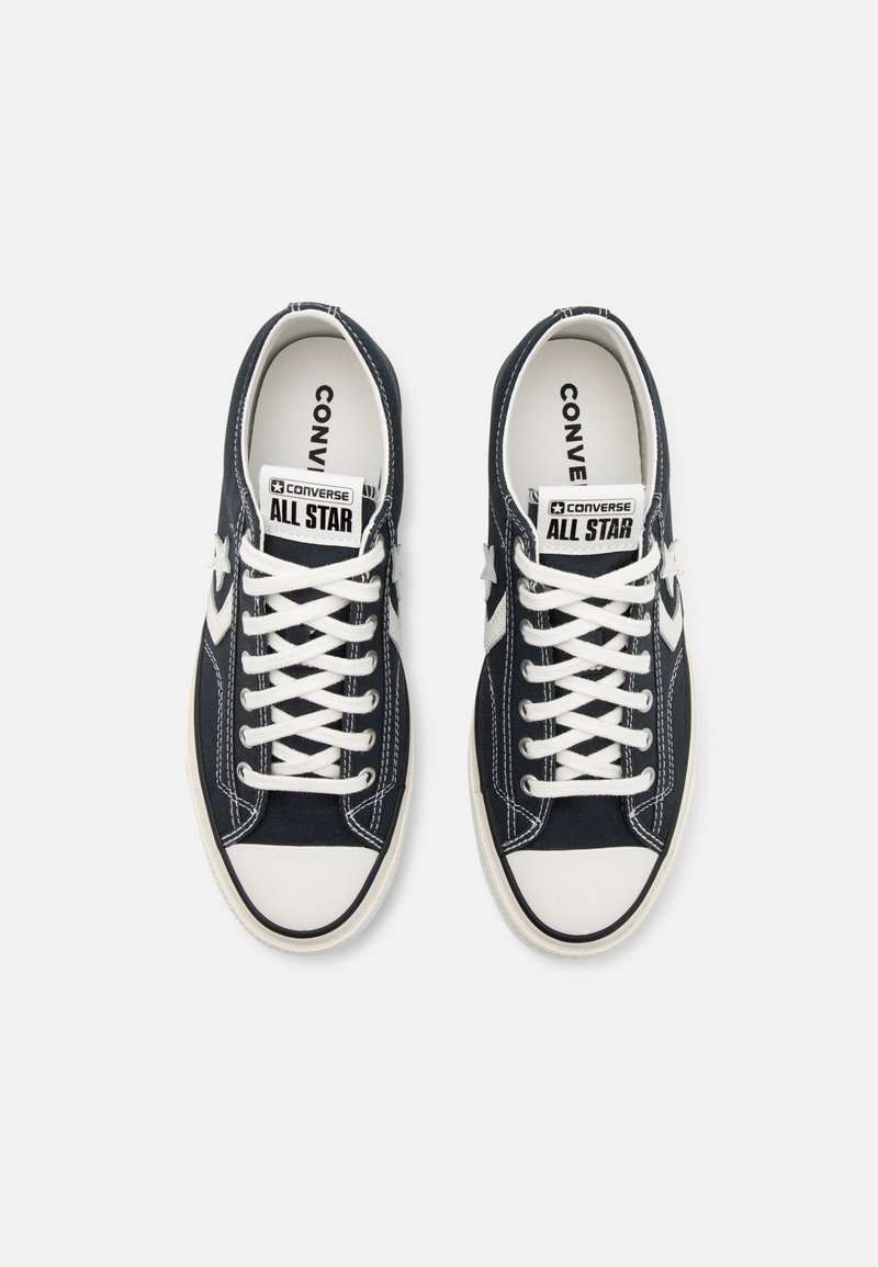 Zapatillas de lona azul oscuro con cordones blancos, puntera de goma y logo "CONVERSE ALL STAR" en la lengüeta y el lateral. Presentan costuras blancas.