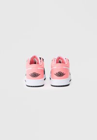 Rožiniai odiniai sportbačiai su juodu logotipu ir akcentais, turintys baltą gumos padą ir paminkštintą apykaklę. Galinis vaizdas rodo dizaino detales.