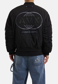 Giubbotto bomber nero con polsini a coste, caratterizzato da logo ricamato "AVRX" e design globale sul retro. Texture opaca con maniche arricciate.