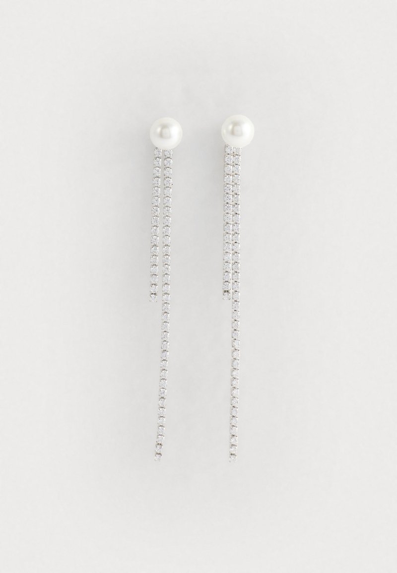 Ασημί κρεμαστά σκουλαρίκια με πέρλα και μακριές αλυσίδες διακοσμημένες με λαμπερούς ρουμπίνους για επιπλέον λεπτομέρεια.