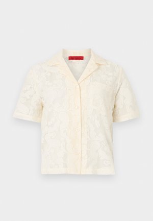 Kremfarvet bluse med korte ærmer i blonder med blomsteragtigt mønster, knapper foran og åben krave.