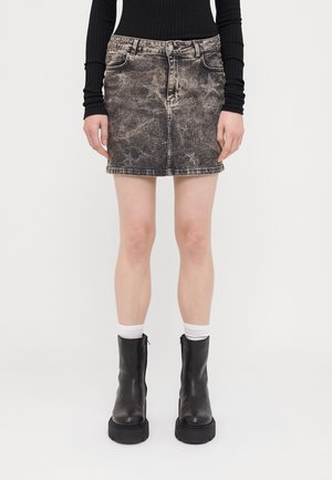 Svart denim mini-skjørt med en falmet design, med frontlommer, beltehemper og rett skull. Brukt med svarte ankelstøvler og hvite sokker.