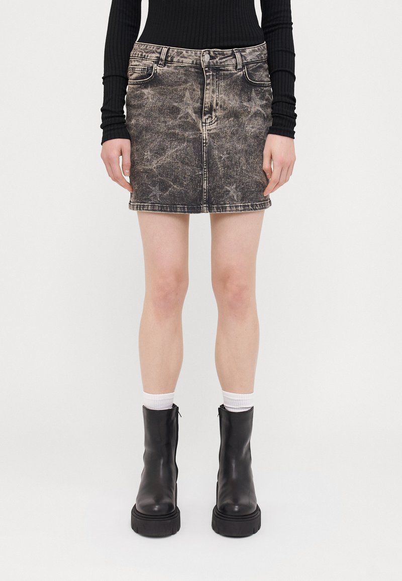 Svart denim mini-skjørt med en falmet design, med frontlommer, beltehemper og rett skull. Brukt med svarte ankelstøvler og hvite sokker.