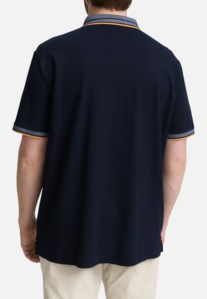 Polo shirt bleu marine avec un col et des ourlets de manches rayés contrastants. Tissu doux au toucher uni et coupe décontractée.
