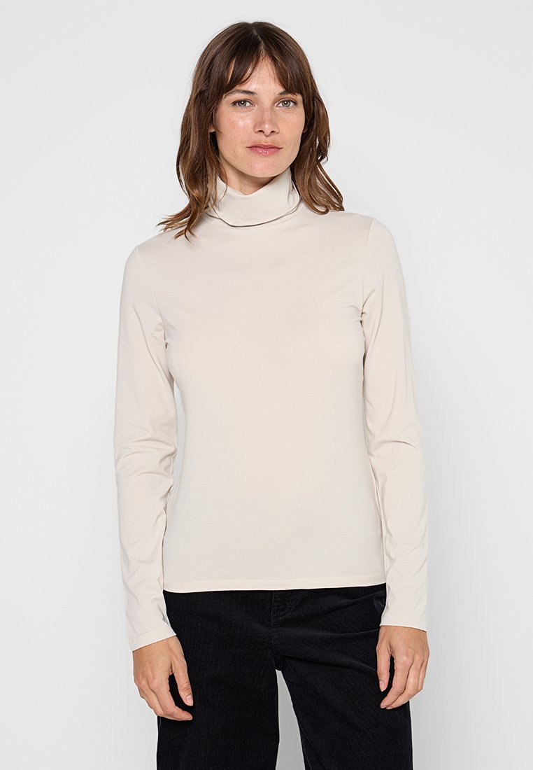 Beige Rollkragenlangarmshirt aus weichem, dehnbarem Stoff. Verfügt über ein einfaches Design mit einer körpernahen Silhouette und ohne sichtbare Muster.