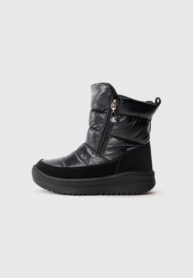 Botte de neige noire imperméable au niveau de la cheville avec un dessus rembourré, fermeture éclair latérale avec le logo CK, et semelle épaisse et robuste.