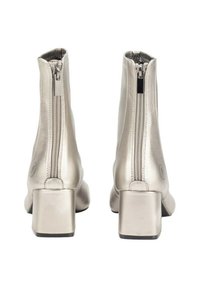 Botines de tobillo plateados metálicos con tacón cuadrado, que presentan una cremallera trasera y un acabado suave. Diseño minimalista sin patrones visibles.
