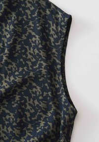 Ärmelloser Stoff mit unregelmäßigem dunkelgrünem und schwarzem Tarnmuster auf hellem grauem Hintergrund.