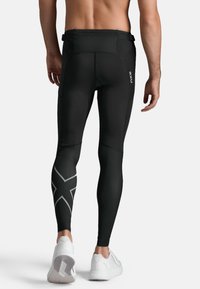 Sorte atletiske leggings med en tætsiddende pasform, der har tekstureret stof, refleksive detaljer og et geometrisk mønster på siderne.