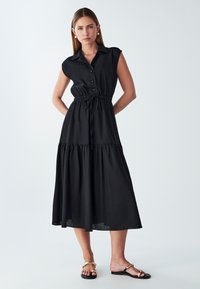 Czarna midi sukienka z krótkimi rękawami, zapięciem na guziki, cinched talia i warstwową spódnicą. Gładki materiał z subtelną teksturą. Minimalistyczny design.