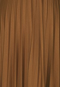 Tessuto plissettato in una calda tonalità di marrone con una texture morbida; le linee verticali creano un design fluido, suggerendo movimento ed eleganza.