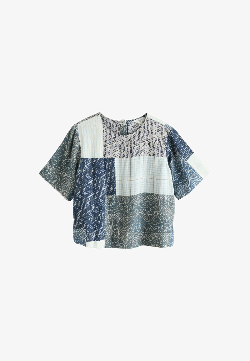 Haut patchwork à manches courtes avec col rond, présentant des carrés de tissu à motifs bleus et blancs mélangés et une coupe ample.