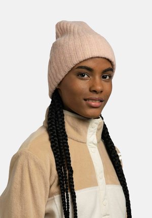 Light pink ribbed beanie with a tapered top, worn with a beige fleece jacket featuring a button-up design and cream accents.