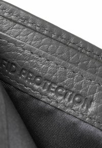 Interior de cuero gris con etiqueta de protección RFID, acabado texturizado y costuras visibles. Fondo de tela suave que realza el contraste.