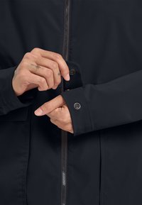 Zwarte waterdichte jas met een ritssluiting aan de voorkant, knoopmanchetten en een gladde textuur. Het ontwerp heeft een getailleerde snit en minimalistische details.