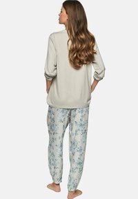 Haut gris clair à manches longues associé à un pantalon crème avec un motif floral bleu. Tissu doux avec une coupe décontractée et des poignets élastiques.