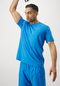Blaues Sport-T-Shirt aus leichtem Stoff, mit Rundhalsausschnitt und kurzen Ärmeln, getragen mit passenden blauen Shorts während eines Trainings.