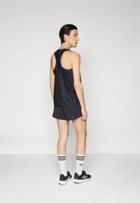Black athletic tank top with an open back, paired with black shorts, white striped socks, and black sneakers. Simple, functional design.