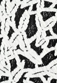 Schwarzer und weißer Stoff mit einem strukturierten Muster aus abstrakten Formen. Das Material scheint gewebt zu sein und hat eine weiche, flauschige Oberfläche sowie kontrastierende Farben.