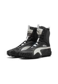 Zwart-witte hoge sneakers met een textuur rubberen zool en uitstekende spikes. Heeft een elastische kraag en een vetersluiting aan de voorkant.