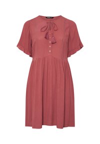 Lyhythelmainen, ruosteenvärinen mekko, jossa on pyöreä pääntie, napitus edessä ja kangastupsuja koristeena. Pleiattupurske tuo lisää tekstuuria.