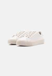 Valged sünteetilised vabaajajalatsid läikiva viimistlusega, ees paelaga kinnitatav, ümara varbaosaga, polsterdatud kraega ja peene kuldse aktsendiga mööda tallavõru.