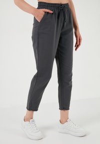Grijze, lichte joggerbroeken met een elastische tailleband, zijzakken en rafelige zoom, gecombineerd met witte sneakers.