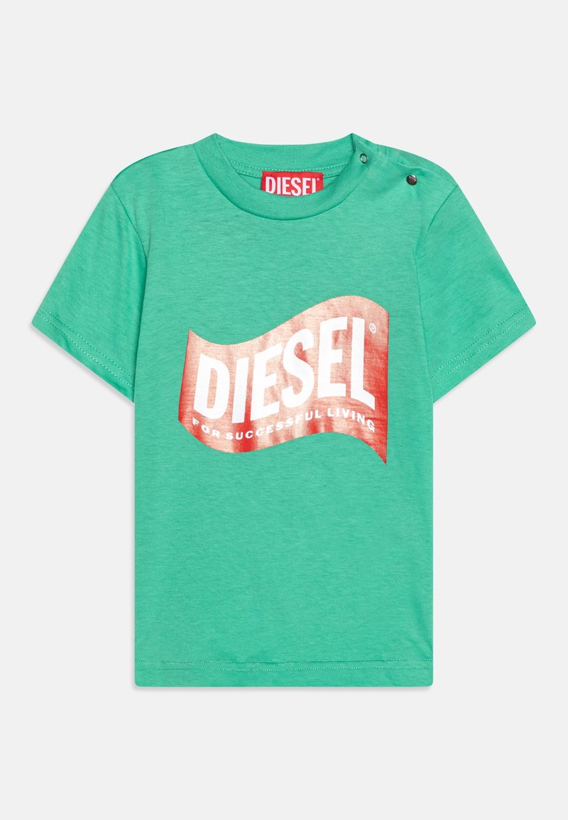 Zelené krátké tričko s krátkým rukávem vyrobené z bavlny. Na přední straně se nachází velké kovové červené logo "DIESEL" ve vlnovém tvaru. Na rameni je detail se zapínáním.