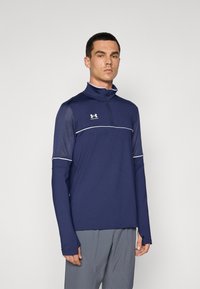 Marineblå langermet treningstopp med halv-zip krage, kontrasterende hvite sømmer og tilpasset design. Laget av elastisk, fukttransporterende stoff.