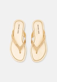Gullfargede thong-sandaler med en strukturert stropp, glatt fotbed og et minimalistisk design. Merkevaren synlig på innersålen.