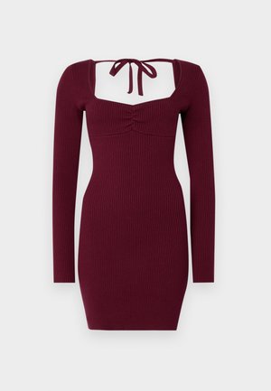 Burgundi színű, bordás ruha hosszú ujjakkal, négyzet alakú dekoltázzsal és megkötő részlettel a háton; a hozzá simuló fazon kiemeli a derékrészt.