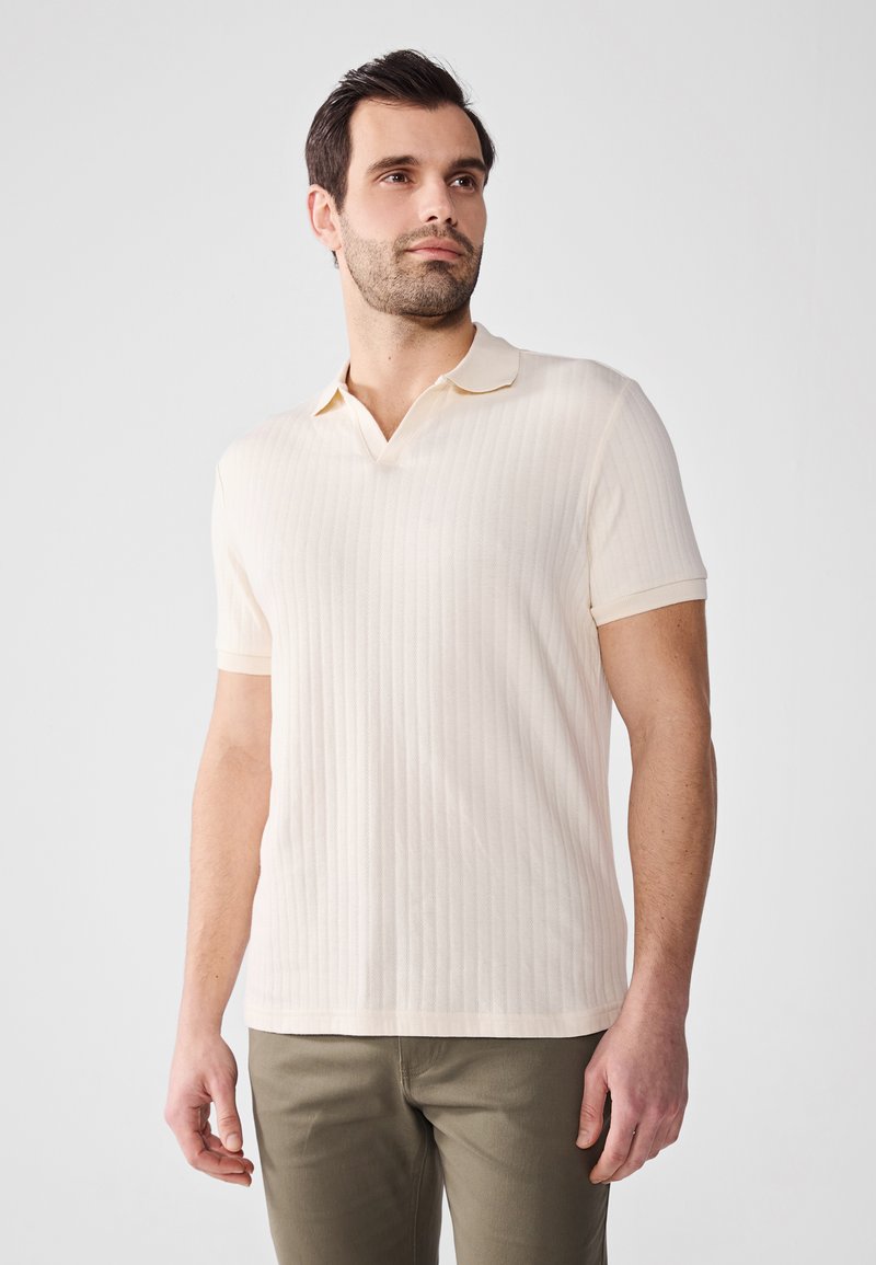 Polo de manga corta en beige claro con un patrón acanalado texturizado. Presenta un cuello clásico y un diseño entallado.