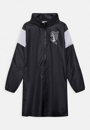 Sort lang Nike vindjakke med frontlynlås, hætte, hvide netpaneler på ærmerne og hvidt "AIR"-logo på brystet.