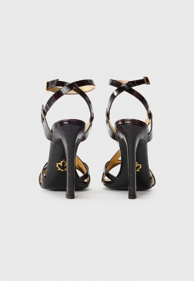 Black heeled sandals with a croc-embossed texture, crossed straps, and a gold-accented insole, featuring a sleek stiletto heel.