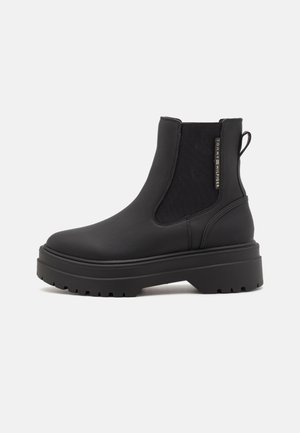 Schwarze Chelsea-Stiefel aus glattem Leder mit elastischen Seitenteilen, einem Zuglaschen und einer dicken, geriffelten Gummisohle.