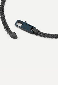 Collier chaîne noir avec un design de maillons texturés. Comprend un fermoir en métal avec un motif géométrique bleu en dessous. Logo visible.